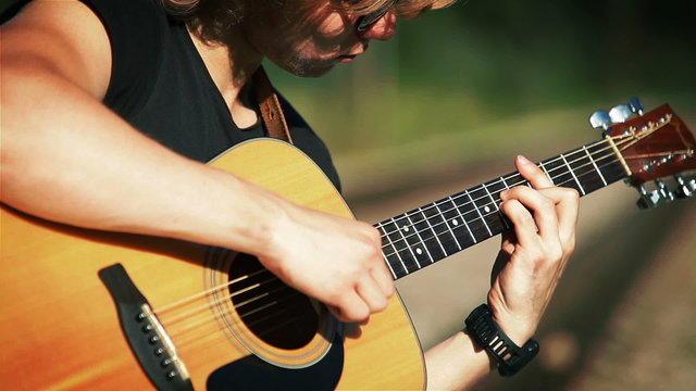 A portrait of a young guitarist performing song played in chords
