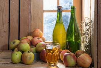bottles and glass of cider with apples