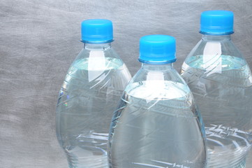 Naklejka premium Plastic bottles of water on gray metal background