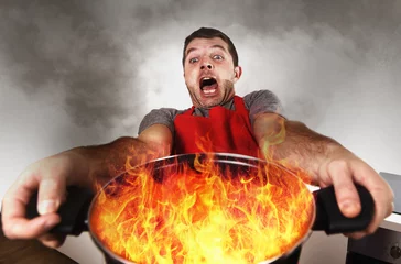 Crédence de cuisine en verre imprimé Cuisinier cuisinier à la maison inexpérimenté avec tablier tenant un pot brûlant dans les flammes avec l& 39 expression du visage de panique de stress