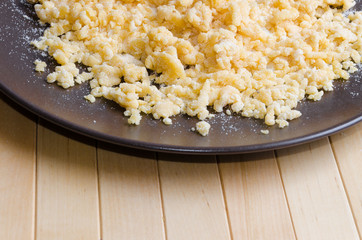 Drip from flour and eggs on dark brown plate on wooden background