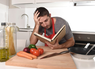 young attractive man at home kitchen reading recipe book in stress