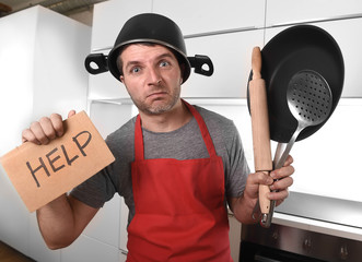 funny man holding pan with pot on head in apron at kitchen asking for help