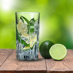 mohito cocktail on wooden table against green background