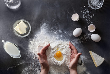 Woman's hands knead dough on table with flour