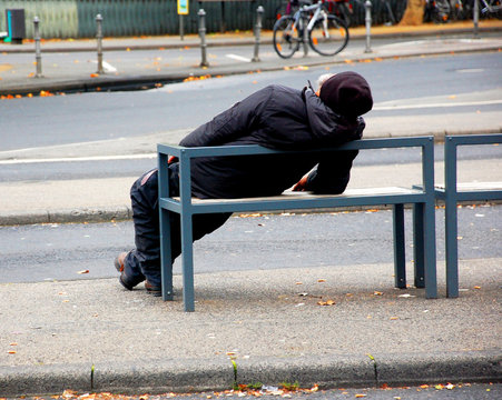 Obdachloser schläft auf Bank in einer Großstadt