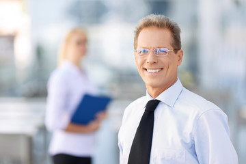Pleasant businessman standing near office 