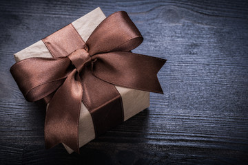 Boxed present tied bow on wood board close up view