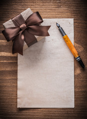 Giftbox brown bow paper fountain pen on vintage wooden board