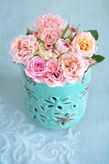 Delicate pink roses in a blue vase on the table.