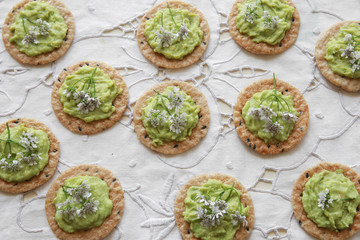 Green avocado crackers with coriander flowers