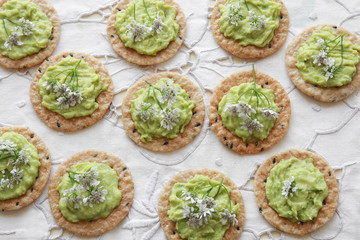 Fototapeta na wymiar Green avocado crackers with coriander flowers