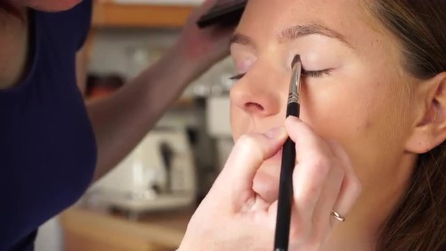 Makeup artist applying with brush eyeshadow on female eye. 4K