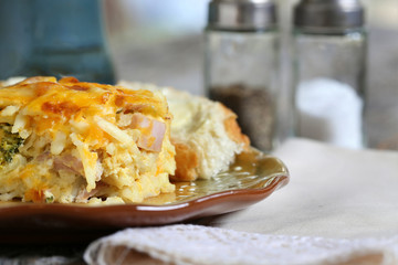 Egg, cheese, peppers, onion and sausage breakfast casserole served with coffee on 

a rustic table plate, fork and napkin