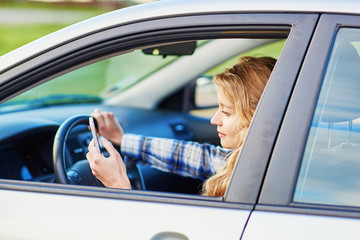 Woman using her smartphone while driving a car