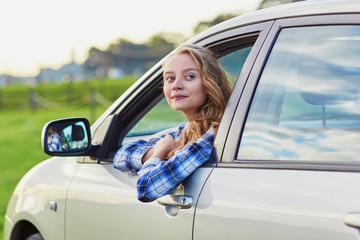 Beautiful young driver looking out of the car