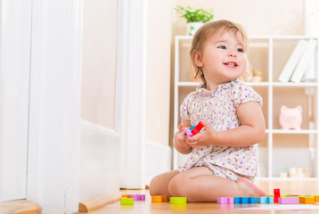Toddler smiling and playing with wooden toy blocks