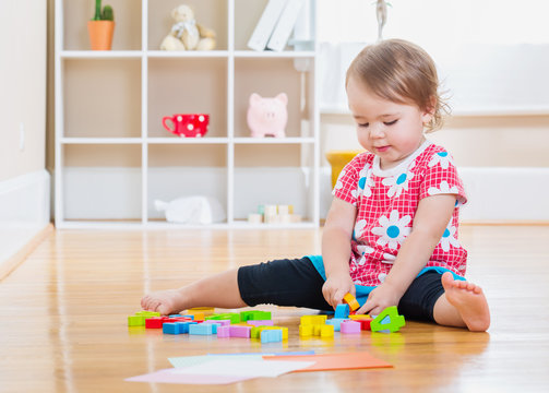 Toddler Girl Playing With Wooden Toy Blocks