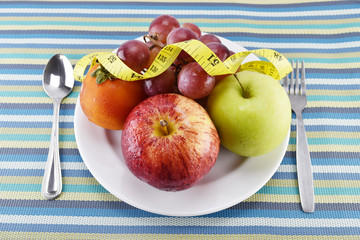grape, tomato, apple and yellow measuring tape concept for healt