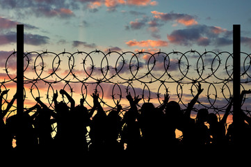 Silhouette of refugees and barbed wire