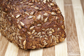 Rye bread mixed from many different healthy ingredients like pieces of soy, rye and wheat flour, sunflower seeds and barley. Studio shot. Photographed on interesting wooden table.
