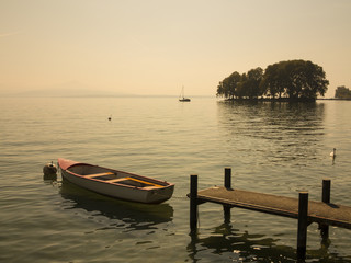 Beautiful scenic view of small island, boat and pier at Geneva lake near to Rolle at Switzerland