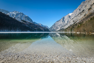 Fototapeta na wymiar Landscape with root in lake water and mountains in background.Leopoldsteiner see,Styria,Austria. 