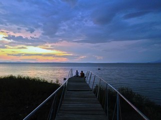 Fototapeta premium Couple watching a sunset, Moyogalpa Pier, Ometepe Island, Nicaragua