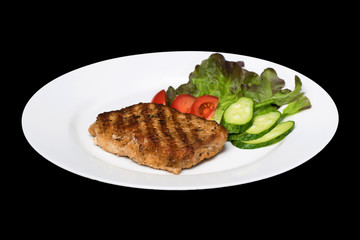 photo of a pork stake on a white plate with a cucumber, tomato a