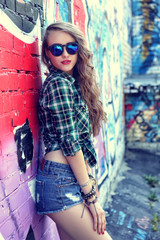 beautiful teenage girl posing near graffiti wall