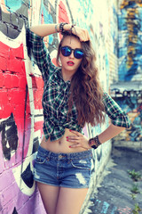 beautiful teenage girl posing near graffiti wall