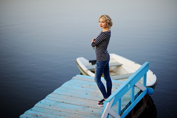 girl in a striped blouse standing on a wooden bridge on a backgr