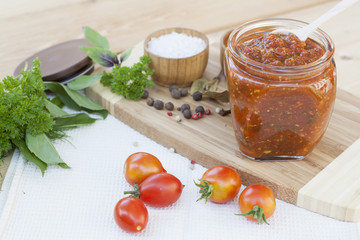 Homemade tomato sauce in glass jar with fresh tomatos, garlic, onion, herbs and spices