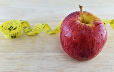 Red apple and yellow measuring tape concept for healthy diet and