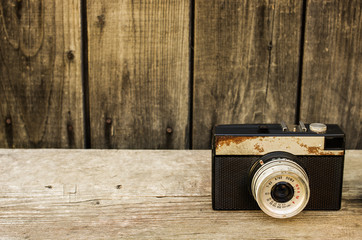 Retro camera on wood table background, old rust hue