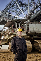 Young and happy worker with a helmet on his head looking over the camera and smiling.