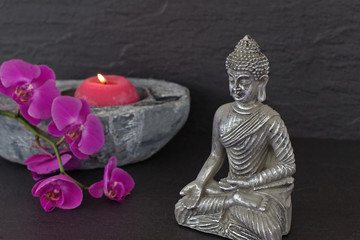 Buddhafigur mit Kerze und Orchidee