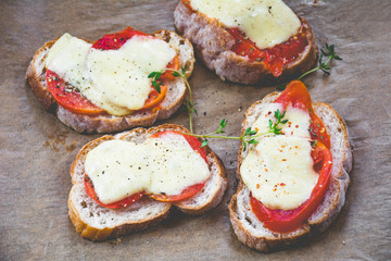 Bruschetta with tomato and mozzarella garnished with fresh thyme leaf and cracked pepper