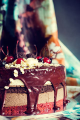 Layer cake decorated with chocolate glaze, cream flowers and che