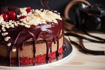 Layer cake decorated with chocolate glaze, cream flowers and che