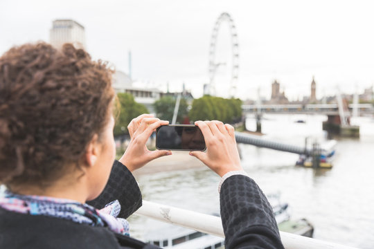 Young woman taking photo of Big Ben in London with her smart pho