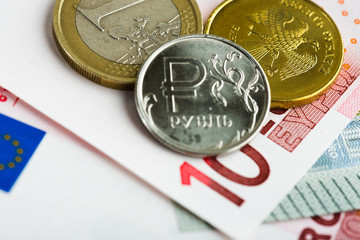  euro and ruble coins on euro banknotes