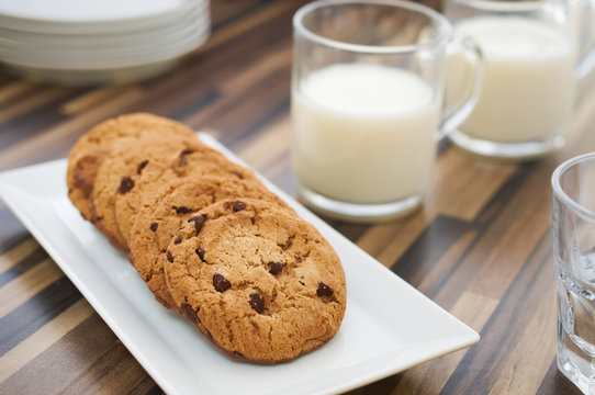 Chocolate chip cookies and milk on dark wood table