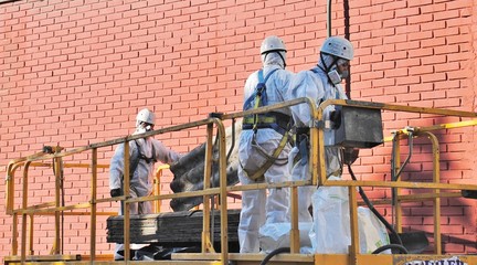 Trabajadores de amianto con placas de fibrocemento dentro de la maquina de elevaci
ón