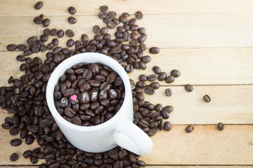 Coffee beans in white mug and wood background