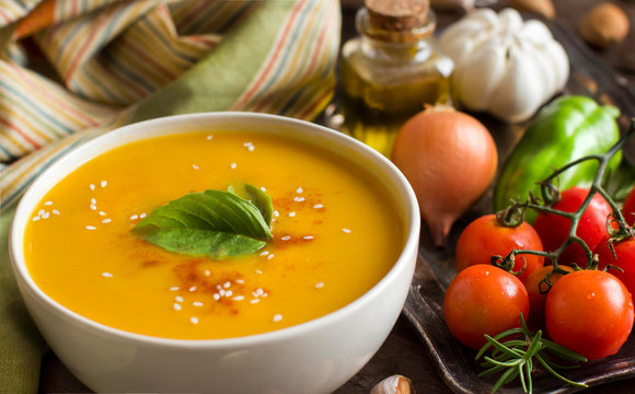 Fresh pumpkin soup with a spoon and vegetables