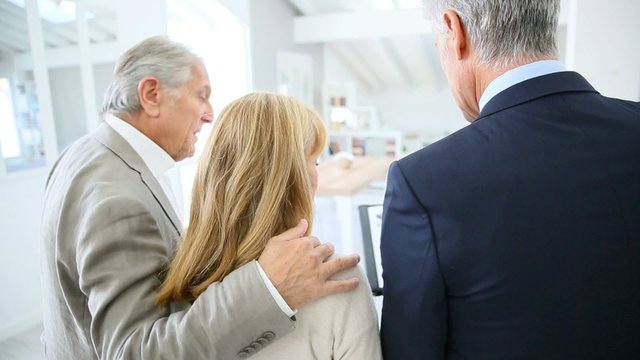 Senior couple with real-estate agent visiting house for sale