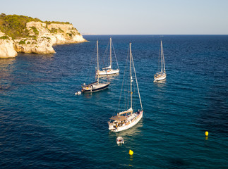 Mar azul y barcos al atardecer en la Playa de la Macareyeta, Menorca, España