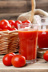Fresh red tomatoes and tomato juice in glass on wooden table