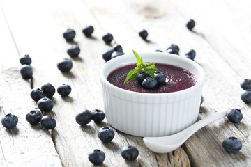 Delicious blueberry mousse in bowl on grey wooden table